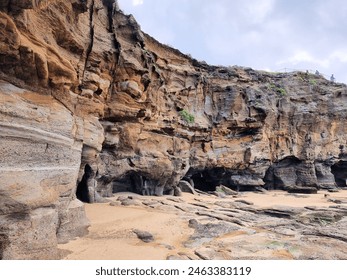 Rock Formation at Caves Beach New South Wales Australia. An eroded cliff face on the beach with small sea caves at the base. - Powered by Shutterstock