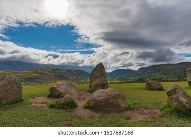 A Rock Formation Known As Swinside Stone Circle Stands In Front Of The Hilly English Landscape Covered In Vegetation As Dramatic Clouds Loom Above In The Lake District, UK.