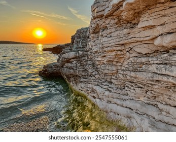 Rock formation with layered texture in sunrise scene at remote beach in Kamenjak National Park. Warm golden glow on cliffs by Adriatic Mediterranean Sea in Premantura, Istria peninsula, Croatia - Powered by Shutterstock