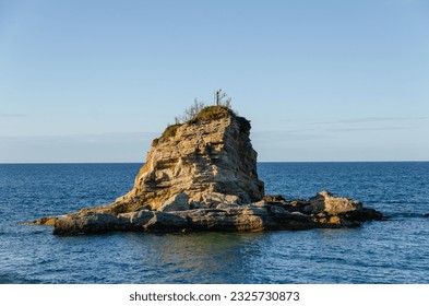 A rock formation in a middle of a sea. Small tree growing out of the top making for a perfect birds nest. - Powered by Shutterstock