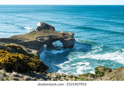 Rock formation on a beach dramatic beautiful Tunnel Beach Dunedin famous blue calm waves 