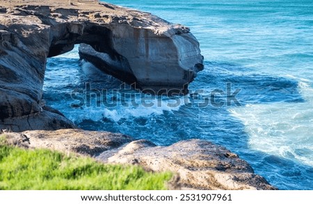 Rock formation on a beach dramatic beautiful Tunnel Beach Dunedin famous blue calm waves 