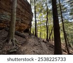 A rock formation, and some trees are seen in the woods in the Hocking Hills, USA, a popular tourist destination