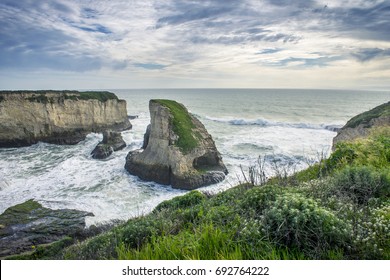 Rock formation surrounded by cliffs and crashing waves