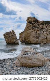 Rock formations and pebble stacks on a coastal beach under cloudy sky