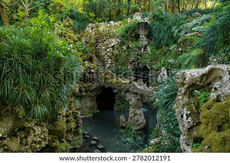 Rock formations, pond and dense vegetation in the water garden of Quinta da Regaleira in Sintra, Portugal.