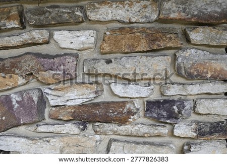 Rock masonry background with multi colored rocks in a cement wal