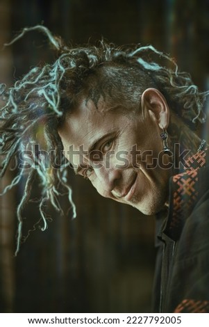 Rock musician. A brutal mature man with ethnic tattoos on his head and neck, with mohawk dreadlocks posing on a studio background. Ethnic rock and punk culture. 