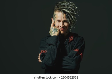 Rock musician. Portrait of a brutal mature man with ethnic tattoos and mohawk dreadlocks on his head posing expressively on a black studio background. Ethnic rock and punk culture. 