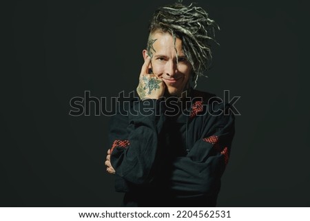 Rock musician. Portrait of a brutal mature man with ethnic tattoos and mohawk dreadlocks on his head posing expressively on a black studio background. Ethnic rock and punk culture. 