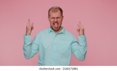 Rock N Roll. Overjoyed Delighted Man 30 Years Old In Shirt Showing Gesture By Hands, Cool Sign, Shouting Yeah With Crazy Expression, Dancing, Emotionally Rejoicing In Success Win Alone On Pink Wall