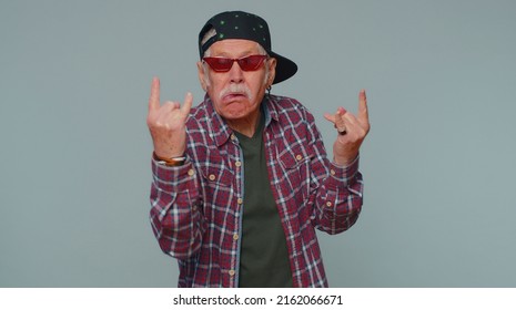 Rock N Roll. Overjoyed Delighted Senior Man 80 Years Old Showing Gesture By Hands, Cool Sign, Shouting Yeah With Crazy Expression, Dancing, Emotionally Rejoicing In Success Win Alone On Gray Wall