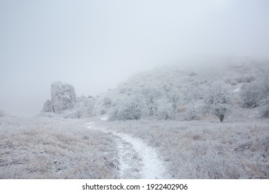 A rock on the edge of a table mountain in Klentnice. Snowy landscape with a hiking trail.