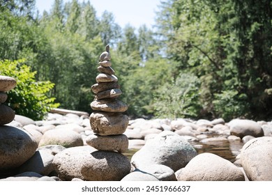 Rock pile or rock stack in front of defocused forest on a sunny day. Pebble tower or rock pyramid. Concept for relaxing, zen, spiritual or yoga. Nature background. Selective focus. North Vancouver BC