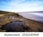 A rock pool next to the Schelde river in Europe. Rocky outcrop riverside with a pool of water trapped at low tide.