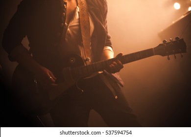 Rock And Roll Music Background, Electric Guitar Player On A Stage With Warm Scenic Illumination, Soft Selective Focus