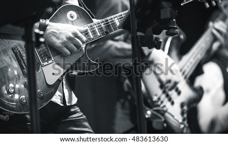 Rock and roll music background, guitar players on a stage, monochrome photo with selective focus