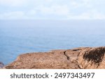 Rock Sea stones with texture surface with blurry blue ocean, cloud sky background,Aerial view Edge Cliff Rock natural stone located part of the mountain with blurred sea beach in sunny day summer