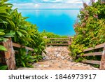 Rock stairs for going down into a blue sea was surrounded by green trees at Lad Koh view point, Samui Island, Thailand. Staircase with wooden handrail. Beautiful sea view from the mountain on island.