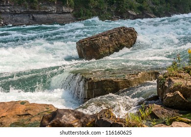 Rock stands against the force of intense white-water rapids in the Niagara river.