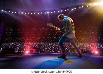 Rock star celebrity on the main stage big music festival. Aroun full stadium of spectators. fans are holding flashlights - Shutterstock ID 1384649900
