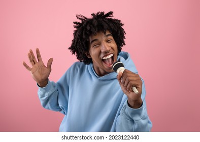 Rock Star. Portrait Of Cool Black Teen Guy Singing Song, Using Microphone, Performing Karaoke On Pink Studio Background. Carefree African American Adolescent Singer Giving Live Music Concert