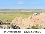 Rock structures and open plain under sunny blue summer sky against the horizon of Badlands National Park, South Dakota.