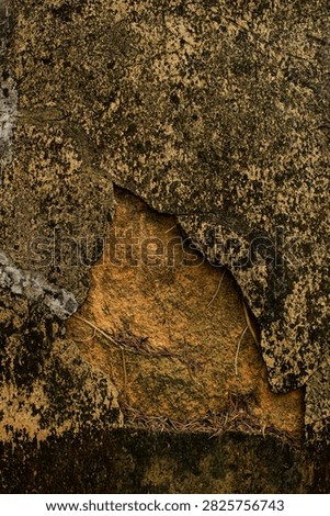 Rock surface with peeling layers showing a brownish area underneath during daylight