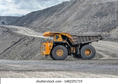 Rock Transportation By Dump Trucks. Large Quarry Yellow Truck. Transport Industry. Mining Truck Is Driving Along A Mountain Road.