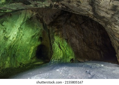 rock wall inside cave Grosse Burghoehle illuminated by the green light of the forest, Balve Sauerland, Germany