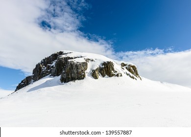 Rock With White Snow Under The Blue Sky