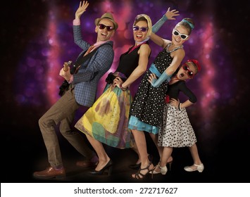 Rockabilly Family Band Having Fun Posing With Guitar And Dancing  In 1950s Style Clothing
