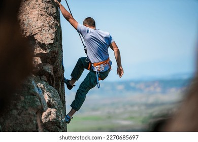 A rockclimber finding a foothold on the steep mountain he's climbing