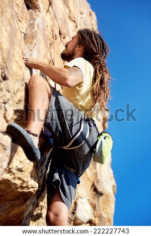 A rockclimber finding a foothold on the steep mountain he's climbing