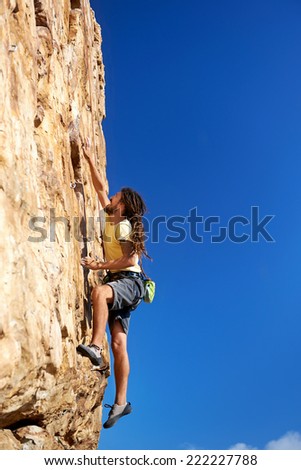 A rockclimbing man reaching for a grip on a steep mountain in the outdoors