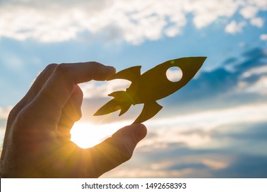 Rocket in hand on a background of the sky of the sun at sunset. On your marks. Concept business idea, success, take-off, promotion.