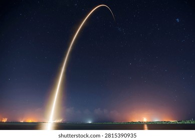 Rocket launch trail streaking across night sky with stars