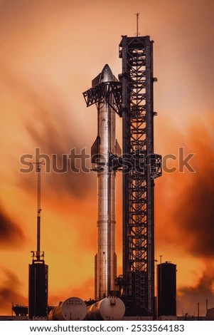 A rocket on a launch pad at sunset, with an orange sky and clouds in the background, capturing the moment before liftoff.