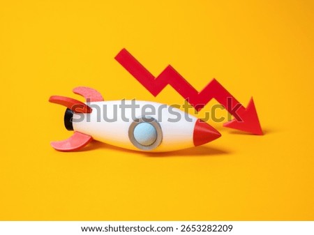 Rocket and red arrow down. Failed startup, failed advertising campaign. Problems in the space industry. Declining investor confidence, or instability in ambitious tech sectors like aerospace.