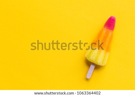 Rocket shaped summer ice lolly on a bright yellow background