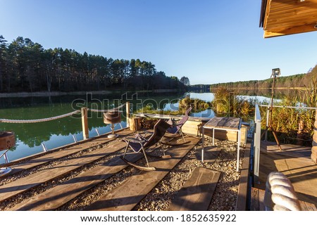 rocking chair on a wooden pier by the lake. house on the water. resting place against the backdrop of an autumn landscape