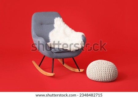Rocking chair, plaid and pouf on red background