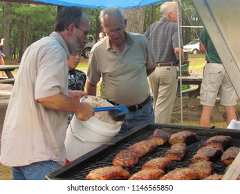 Rockingham County, VA, USA - 8/6/2011: Basting Pork Roasts In Preparation For A Congregational BBQ At The Church Retreat
