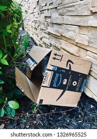 Rocklin, CA, USA - March 1, 2019: Stolen And Opened Amazon Prime Box Package Tossed Behind A Bush Next To The Building Wall.