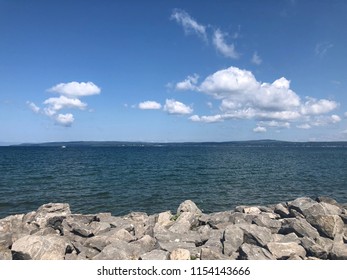 Rocks along Little Traverse Bay in Petoskey, MI with beautiful puffy clouds in the blue sky. - Shutterstock ID 1154143666