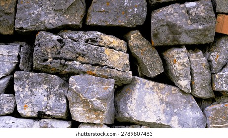 Rocks are arranged closely to create a solid wall structure. The surface shows different textures and colors, indicating age and weathering. The setting is outdoors in natural light.