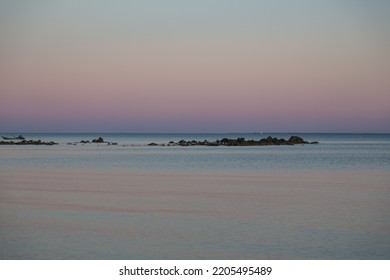 Rocks with birds against the beautiful sky after sunset reflecting in the Atlantic ocean at Carnac, Brittany, France -mystical coastline in pastel colors 