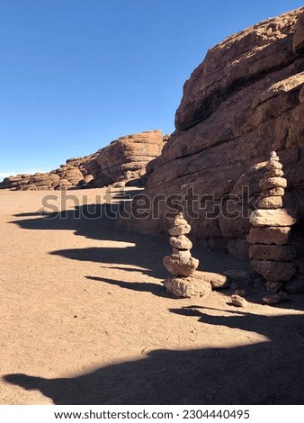 Rocks in a desert-like terrain, characterized by earthy brown tones. Two small stone towers stand in front of the rocks. A dry and arid landscape, defined by the simplicity and beauty of nature.