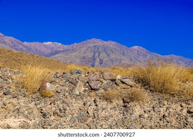 rocks and dry grass tufts in autumn mountains scene at sunny day.