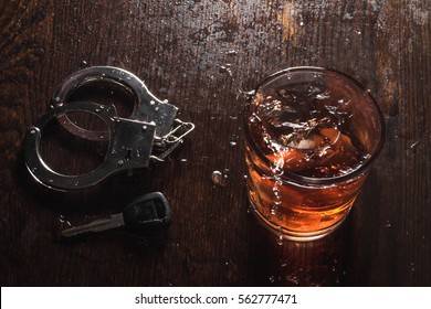 Rocks glass of whisky with handcuffs and keys symbolizing drunk driving arrest